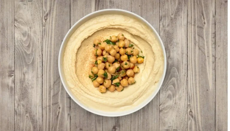 What is hummus — creamy chickpea and tahini dip served at Aladdin Mediterranean Cuisine in Houston, topped with olive oil and paprika.
