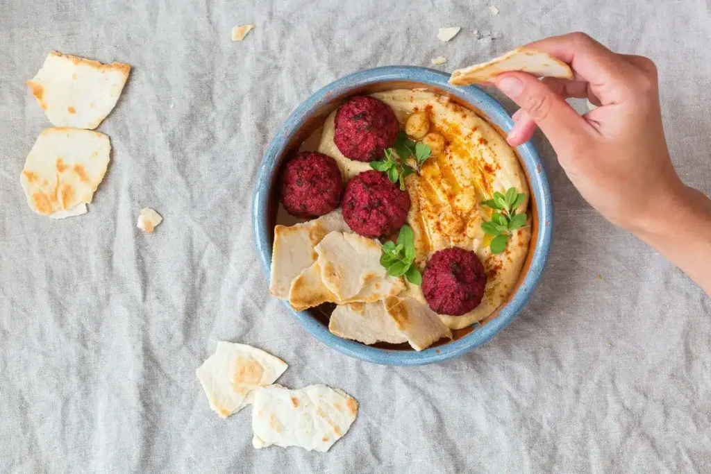 Vibrant beet falafel served on creamy hummus with pita bread, ideal for vegan Mediterranean recipes. halal food near me.