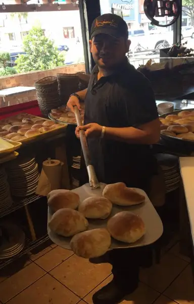 Aladdin Houston baker holding freshly baked pita bread inside the restaurant