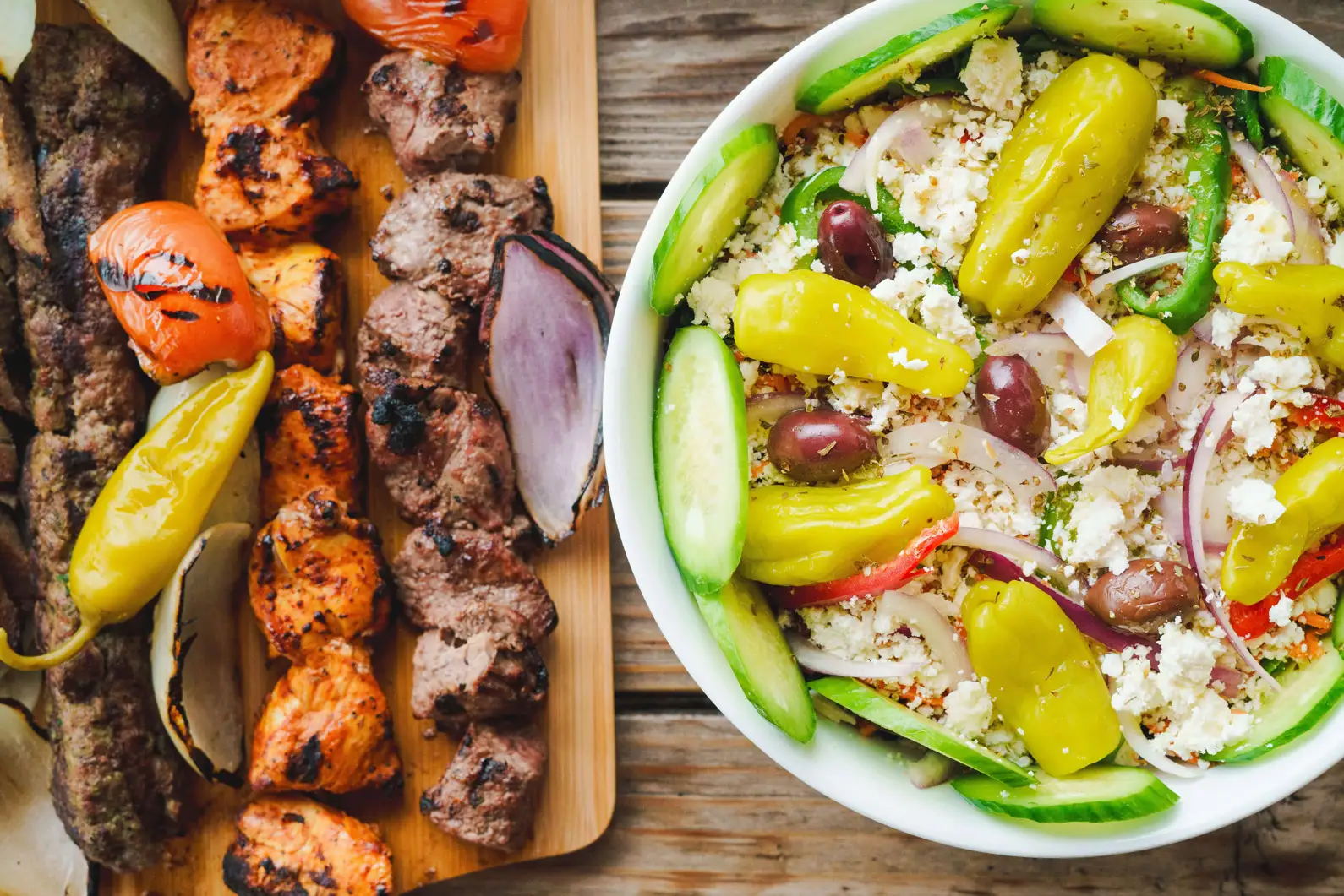 Fresh greek salad beside a mix shish kebab plate