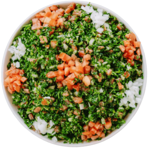 Tabouli Salad a chopped parsley mixed with diced tomatoes and onions in a white bowl