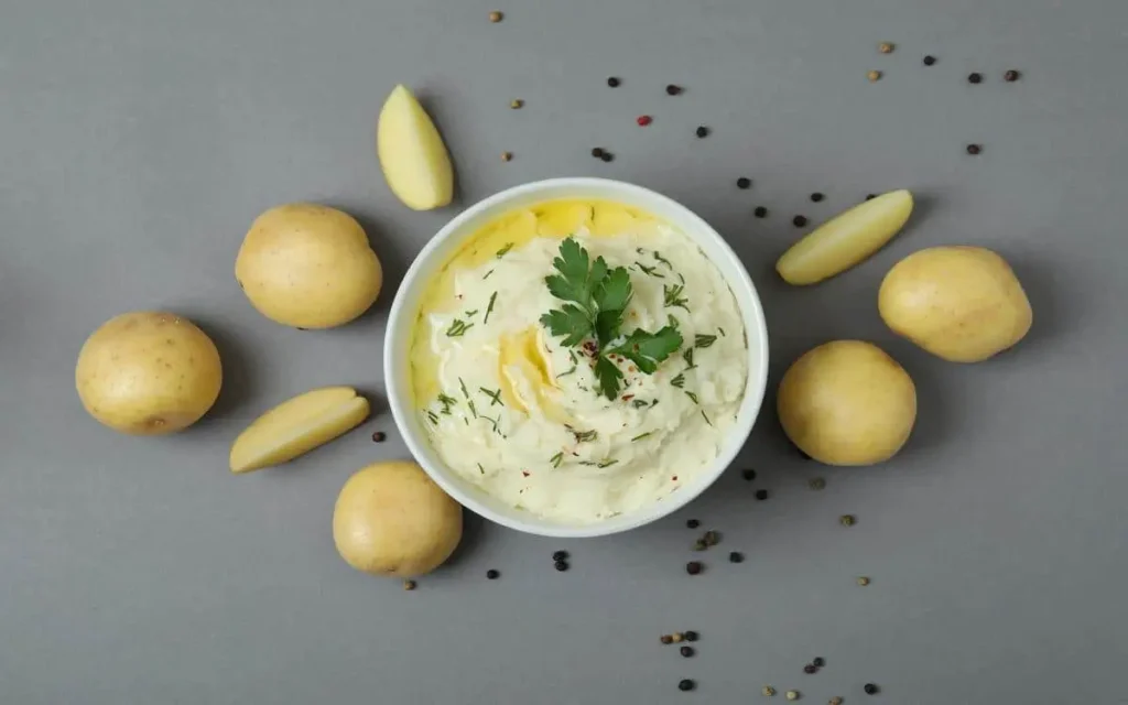 Skordalia Mediterranean potato dip garnished with fresh herbs, olive oil drizzle, surrounded by potatoes and spices at Aladdin Montrose