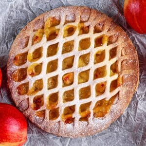 Aladdins Houston Apple Pie with lattice crust, powdered sugar, golden apple filling, and red apples
