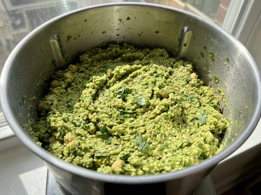 Coarsely ground bright green falafel mixture in a food processor for a homemade falafel recipe